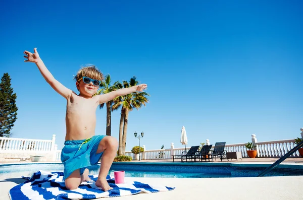 Happy Kid Sitting Pool Sunglasses Striped Towel Raise His Arms — Stock fotografie