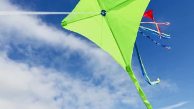 Group of many beautiful color red green orange kites fly on the string over blue sky with clouds
