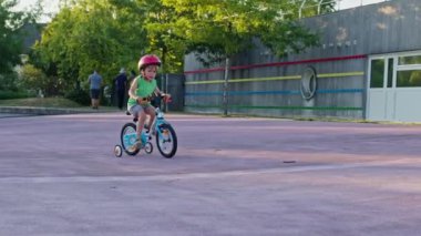 Küçük mutlu çocuk kaykay parkında direksiyon ve pedallarla bisiklet sürmeyi öğreniyor.