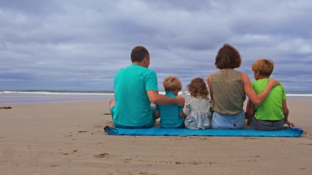 Çocuklu Bir Aile Kumsalda Bir Arada Oturur Ellerini Arkadan Kaldırır — Stok video