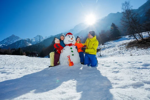 有两个孩子的家庭 父母一起堆雪人 在高山上玩耍 — 图库照片