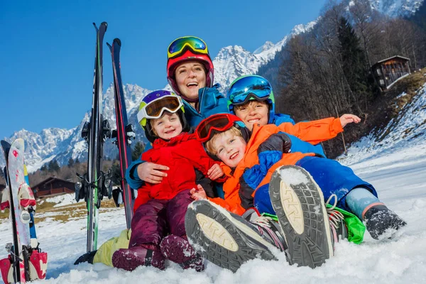男孩和小孩穿着运动服坐在雪地里 头上戴着钢盔 笑着拥抱高山 — 图库照片