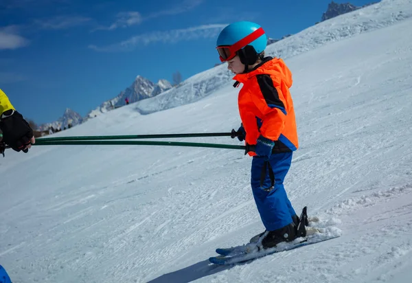 子供のプロフィールビューは スキーヘルメットとマスクを着用する方法を学ぶポールを保持するインストラクターとスキーを学ぶ — ストック写真