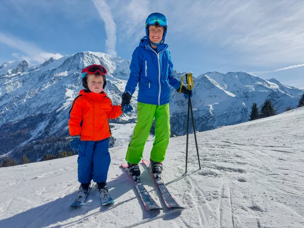 哥哥是滑雪者 他的小弟弟教他骑在法国山上阳光灿烂的斜坡上 — 图库照片