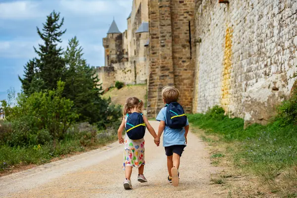 孩子们带着背包去度假 沿着法国南部的卡卡松内 Carcassonne 要塞城市的高墙跑步观光 — 图库照片