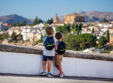 Sırt çantalı genç gezginler, yazın İspanya 'ya yaptıkları gezide Ronda' nın ufuk çizgisine arkadan bakıyorlar.