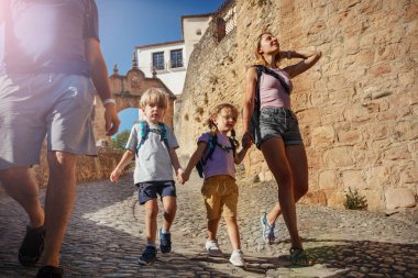 İki çocuklu turist ailesi eski güneşli Ronda kasabasında yürüyor, Güney İspanya 'da yaz tatilinin tadını çıkarıyorlar.