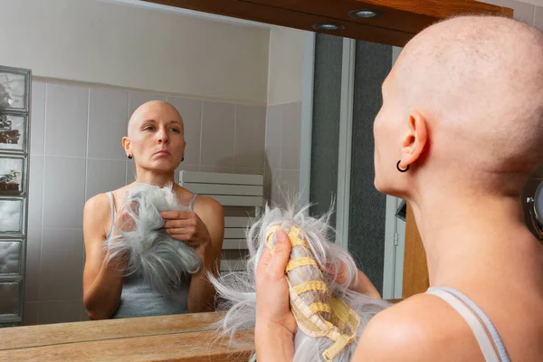 Una Persona Con Testa Rasata Sta Contemplativamente Tenendo Una Parrucca — Foto Stock