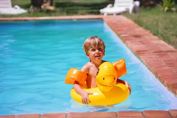 Young Boy Floats Happily Swimming Pool Bright Yellow Duck Inflatable — Stock Photo, Image