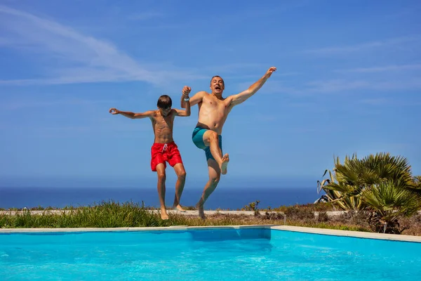 Two Individuals Father Son Joyfully Leaping Swimming Pool Sunny Day — Stock Photo, Image