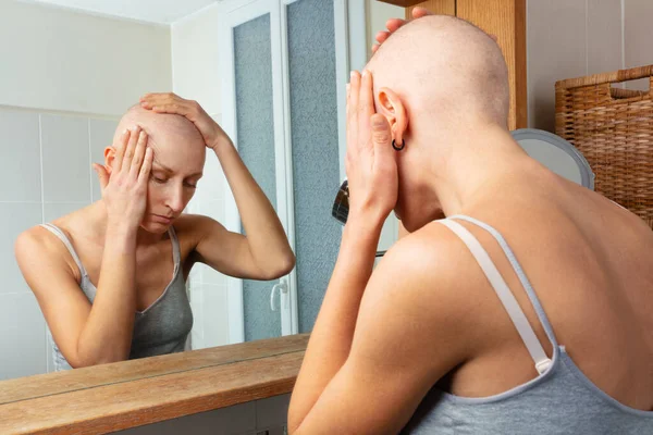 化学療法によって引き起こされる脱毛症の反射的な女性は慎重に裸の頭に置かれた浴室の鏡の彼女の類似性を観察します — ストック写真
