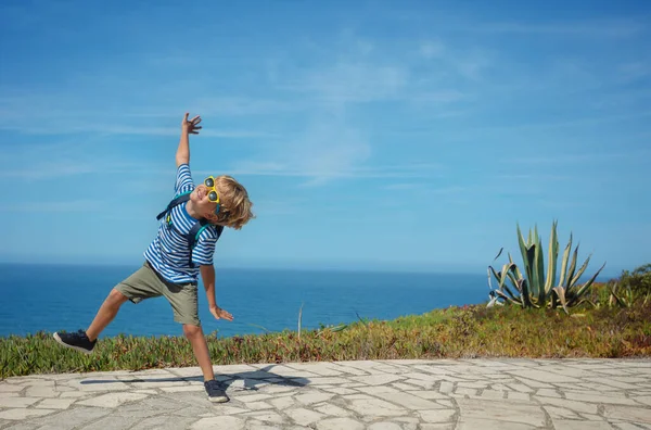 快乐的金发碧眼的男孩身穿夏装 戴着太阳镜在海上跳舞 他对葡萄牙的度假感到兴奋 — 图库照片