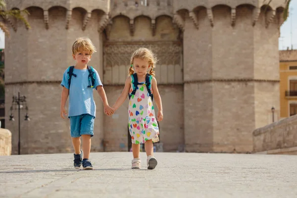 2人の子供が手を握り スペインでの夏の旅行中に有名なトレス セラノスの前に晴れたバレンシアを歩きます — ストック写真
