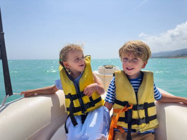 Çocuklar, neşeli erkek ve kız ceketli İspanya 'da güneşli bir günde tekne gezintisinin tadını çıkarıyorlar.