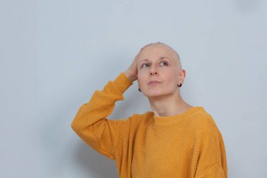 Hayal gören tüysüz kızın portresi göğüs kanserine karşı kazanılan zaferden sonra gri duvara karşı kendinden emin görünüyor.