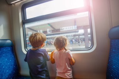 Bir erkek ve bir kız kardeş bir trende seyahat ediyorlar, pencereden dışarı bakıyorlar, manzaradan büyülenmişler.