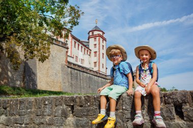 İki çocuk Wurzburg, Almanya 'daki yaz aile gezileri sırasında Marienberg' in taştan duvarında oturuyordu.