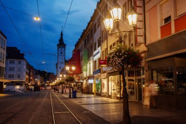 Avrupa 'da Wurzburg şehrinde, arka planda tarihi binalar ve saat kulesi bulunan canlı bir gece sahnesi, Bavyera, Almanya