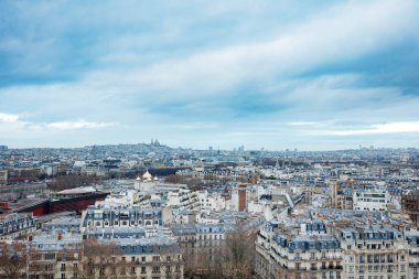 Klasik Paris tarzı Hausmann binaları karakteristik çatıları ve bulutlu ufuktaki Montmartre tepesinde yer alan Sacre-Coeur Bazilikası.