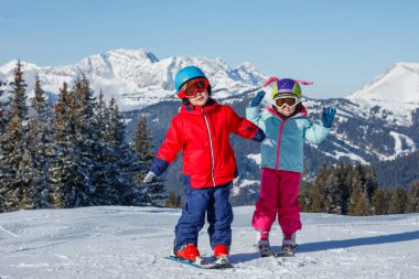 İki küçük çocuk, kask takan kardeşler ve kış giysileri tatillerde manzaralı dağlarda karlı maceraya hazır.
