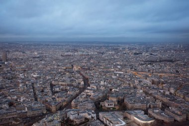 A high-angle shot displaying a European metropolis Paris enveloped in the soft glow of evening, with closely packed buildings and curving streets at winter dusk clipart