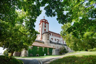 Taştan bir kale olan Marienberg, Almanya 'nın Wurzburg Bavyera şehrinde asfalt bir yol ile yemyeşil yapraklar tarafından çerçevelenmiştir.