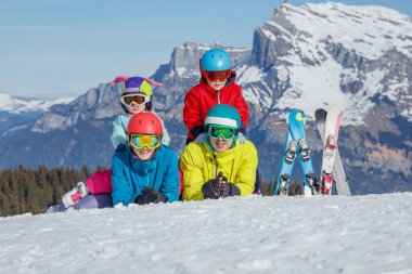 Renkli kayak kıyafetleri içinde dört gülen kayakçı soğukta neşeli bir kış aktivitesinin tadını çıkarıyorlar.
