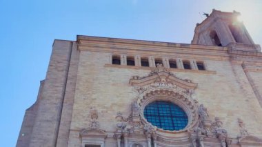 Güneş ışınları eski Girona Katedrali 'nin klasik barok mimarisini süslenmiş bir gül penceresi ve ayrıntılı heykelleriyle aydınlatır.