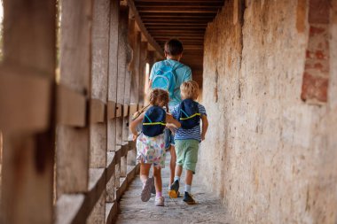 Sırt çantalı üç çocuk Rothenburg ob der Tauber, Almanya, Bavyera geçidi boyunca yürüyorlar.