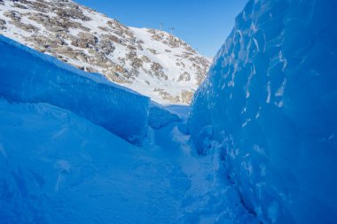 Kocaman, parlak mavi buz duvarlarıyla çevrili buzlu bir yol.