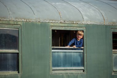 Mutlu çocuk pencereden sarkmış, yaz tatili boyunca trenle seyahat etmek için heyecanlı.