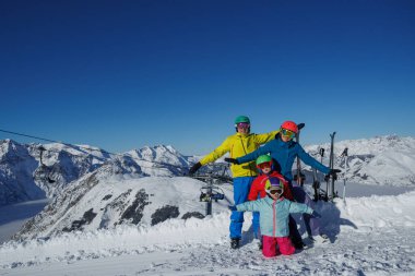Dört kişilik bir grup, anne, baba iki çocuk, karla kaplı tepelerin arasında eğleniyorlar.