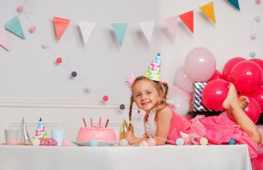 Masada pembe giyinmiş bir çocuk mumlu bir doğum günü pastasına hayran kalır. Duvardan geçen renkli kiraz çiçeğiyle güzelleşen bir ortam.