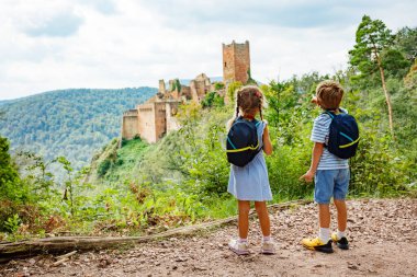 Sırt çantası takan genç bir kız ve oğlan Fransa 'nın Alsace bölgesindeki Avrupa Alsace bölgesinde Saint-Ulrich kalesi ile birlikte manzaralı bir patikada ele geçirildi.
