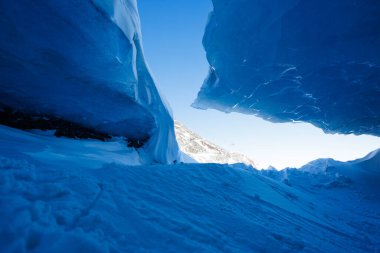 Eski bir buzul mağarasının içi gökyüzünün parlak mavi rengini gösteriyor.