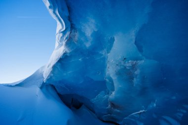 Eski dağ buzulunun bir parçası olan mağara girişinden içeri süzülen sakin güneş ışığıyla görkemli bir buz mağarası.