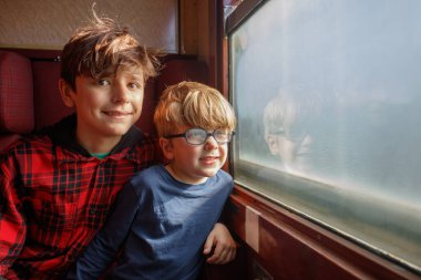 İki kardeş, hareketli bir şekilde tarihi yerleri tartışıyorlar ve yaz tatili boyunca pencereye bakıyorlar.