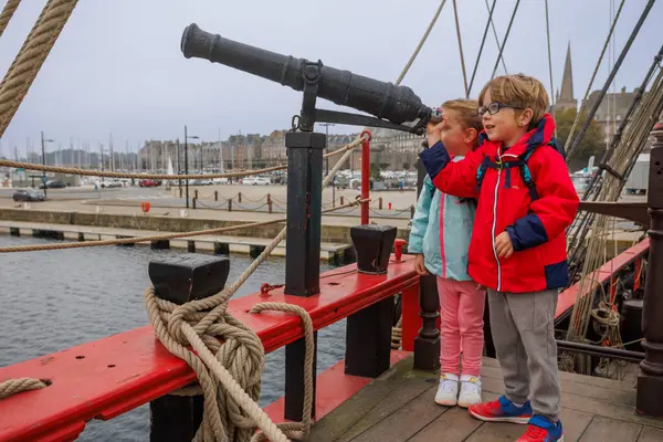 Parlak ceketli ve sırt çantalı iki çocuk Saint-Malo, Bretagne, Fransa 'da bir gemi güvertesini geziyor.
