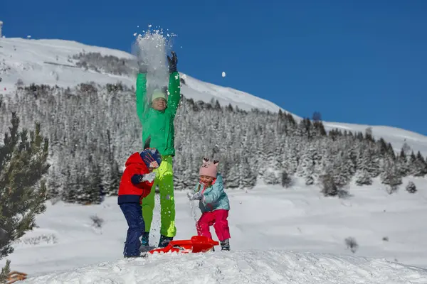 Mutlu erkek ve kız arkadaşlar tatillerde dağ kayak merkezinde karla oynarlar.