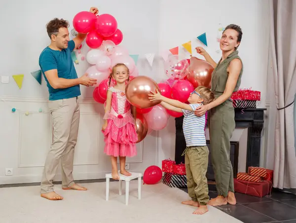 Canlı dekorasyonların arasında, ailesi ona gururla bakarken genç bir kız hediyeler alır.