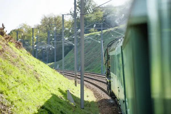 Otomobil penceresinden güneşli gün ışığında demiryolu eğrisinde yeşil buhar motoru retro lokomotifi