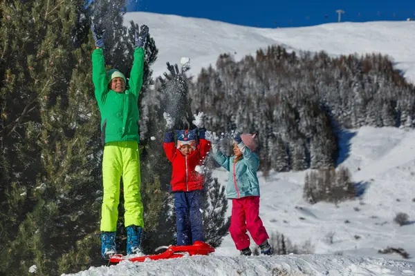 Mutlu çocuklar kayak merkezindeki Noel tatillerinde karlı tepeye kar attıkları için heyecanlılar.