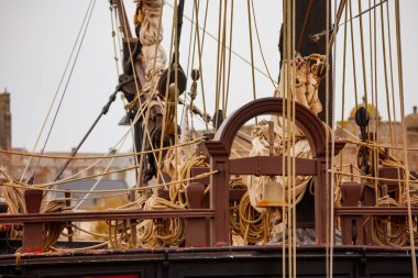 Yakın plan bir gemi donanımı, birbirine dolanmış halat ve makaraları vurguluyor bulanık şehir manzarasına karşı Saint-Malo, Bretagne, Fransa