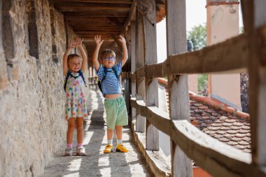Sırt çantalı üç genç gezgin şehir duvarında dar bir taş geçidi keşfediyor, Rothenburg ob der Tauber, Almanya
