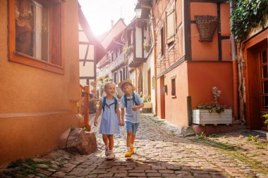 Eski şehirde gezen sırt çantalı iki çocuk binaların geleneksel yarı ahşap tarzı, büyüleyici köylerde renkli panjurları var. Fransa 'nın Alsace bölgesinde saksı bitkileri ve çiçekler var.