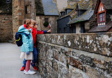 Fotoğrafta iki genç sırt çantası takıyor, tarihi bir binaya bakıyor, biri çatıya bakıyor.
