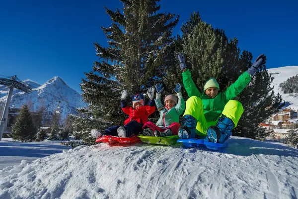 Kardeşler, iki erkek çocuk, kızlar kızaklarda kayarak, güneşli yamaçları ve uzak tepeleri alarak eğleniyorlar.