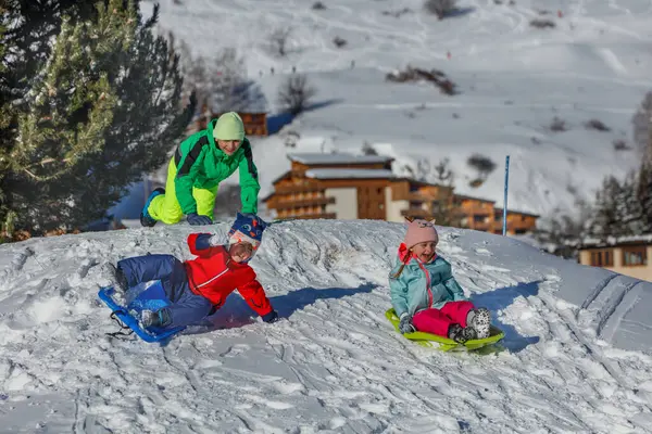 Kar giysileri içinde üç çocuk el değmemiş bir tepenin tepesinde renkli kızaklarda çömelmiş, arkalarında tebeşirler yükseliyor..