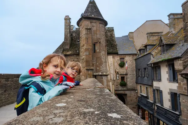 Serin bir günde, sırt çantalı iki genç okyanus kıyısındaki antik bir manastırı keşfederken gülümserler.