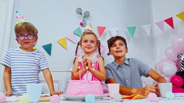 Genç bir kızın dilek tuttuğu bir doğum günü partisi sahnesi. Mumları üflerken, etrafında şapkalı iki çocuk alkışlıyor.